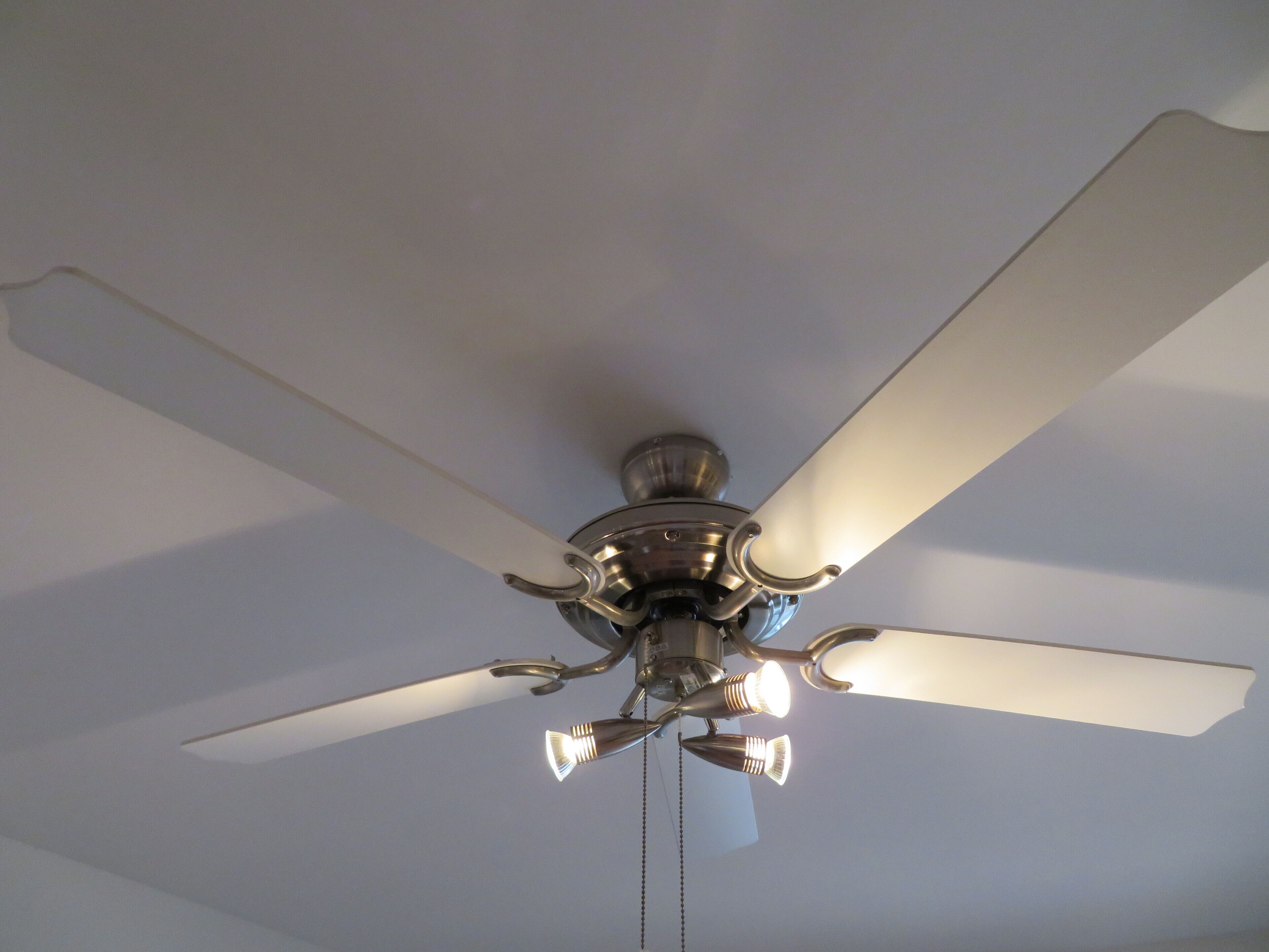 A ceiling fan with four blades and a light fixture.