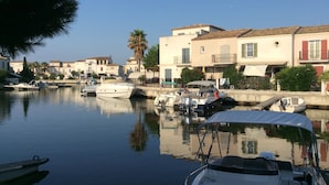 A marina with boats docked, calm water, and buildings with balconies and windows in the background. - Marina Petite Belge à Aigues Mortes (incl city bikes on request) (Aigues-Mortes)