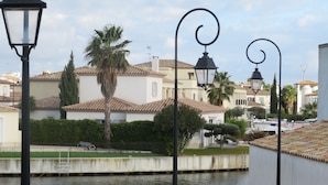 A canal with buildings and palm trees in the background. - Marina Petite Belge à Aigues Mortes (incl city bikes on request) (Aigues-Mortes)