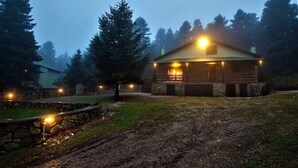 Eine rustikale Holzhütte mit Steinuntergrund, einer Holzterrasse und einer Veranda.