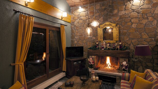 Ein gemütliches Wohnzimmer mit Kamin aus Stein, einem Fernseher und einer bequemen Sitzecke.