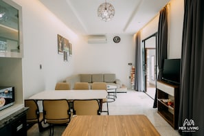 Relax in a stylish living area with a sofa, chairs, dining table, and flat-screen TV.