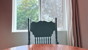 Une table à manger avec une chaise placée devant une fenêtre donnant sur des arbres.