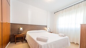 Une chambre d’hôtel avec un grand lit, deux tables de chevet avec des lampes, une tête de lit en bois et un rideau à la fenêtre.