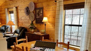 A cozy cabin interior with a wooden dining table set for six, surrounded by wooden chairs.