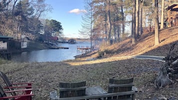 Une zone au bord du lac avec un banc en bois, un petit quai et une cabane en arrière-plan.