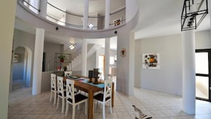 A spacious dining area with a high ceiling and a central table surrounded by chairs. - Blue Lily Langstrand Self Catering (Walvis Bay)