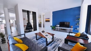 A modern living room with a sofa set, a coffee table, and a TV. - Blue Lily Langstrand Self Catering (Walvis Bay)