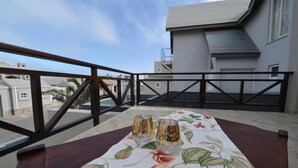 A balcony with a table set for two, overlooking a residential area. - Blue Lily Langstrand Self Catering (Walvis Bay)