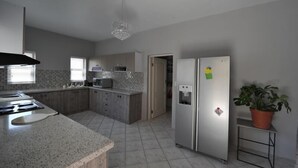 A modern kitchen with granite countertops, stainless steel appliances, and a tiled backsplash. - Blue Lily Langstrand Self Catering (Walvis Bay)