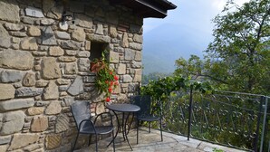 A stone building with a small balcony, two metal chairs, and a table. - Hotel Il Fondaccio (Lizzano in Belvedere)