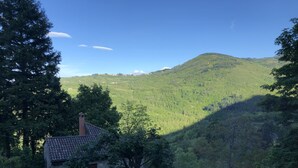 A stone house with a tiled roof, surrounded by lush greenery and a mountainous backdrop. - Hotel Il Fondaccio (Lizzano in Belvedere)