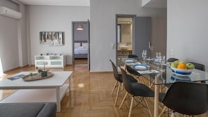 Un espace repas moderne avec une table en verre, des chaises noires et un saladier rempli de fruits.