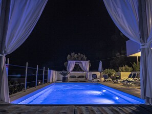 An outdoor swimming pool at night with blue lighting, surrounded by lounge chairs and a canopy. - Last-minute offers / Pet-friendly / VERY low low-season prices (Komarna)