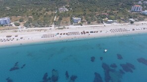 Een privéstrand, ligstoelen aan het strand, parasols, beachvolleybal
