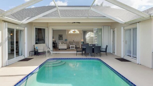 A covered swimming pool with a patio area, sliding glass doors, and a view of the interior living space.