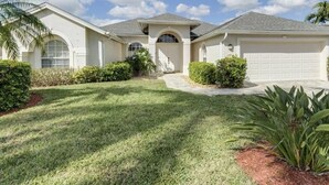 A two-story house with a garage, a covered entryway, and a well-maintained lawn.