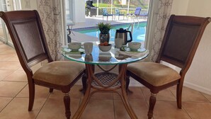 A dining area with a glass table and two wooden chairs with cushioned seats.