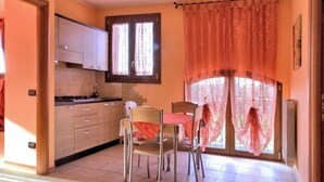 A kitchen with a dining table and chairs, a window with curtains, and cabinets. - Spring Apartment (Agriturismo Il Melograno) (Venezia)