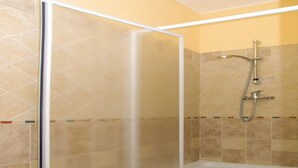 A shower area with a glass door, tiled walls, and a handheld showerhead. - Spring Apartment (Agriturismo Il Melograno) (Venezia)