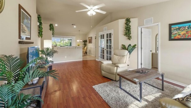 A spacious living room with hardwood flooring, a ceiling fan, and a large window offering a view of the outdoors. - deal for remote working/studying and native plants/wildlife watching (Cape Coral)