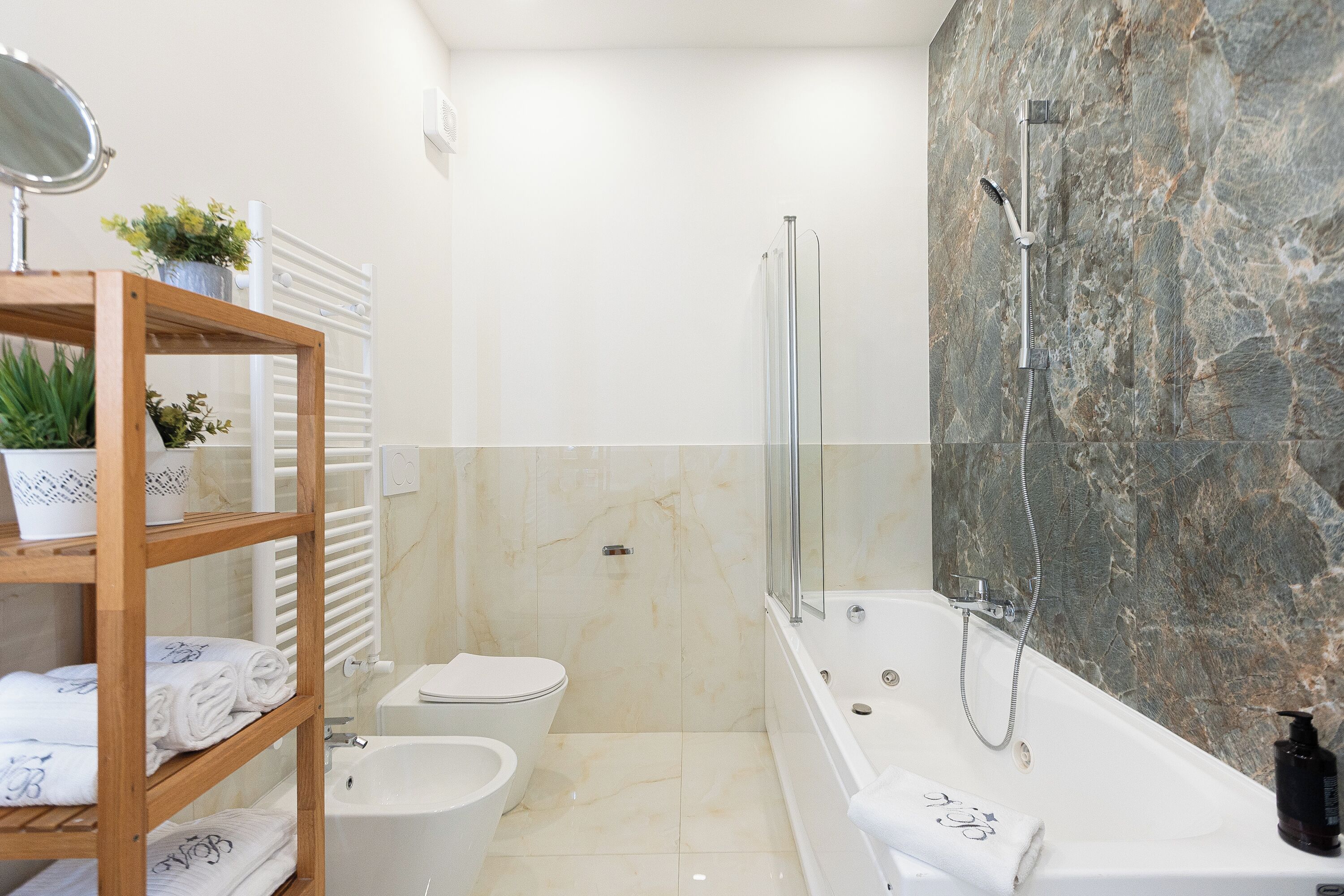 Une salle de bain moderne équipée d’une baignoire, d’une douche, de toilettes et d’un meuble-lavabo avec un miroir et un porte-serviettes.