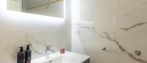 A bathroom with a white sink, two black soap dispensers, a mirror, and a towel rack.