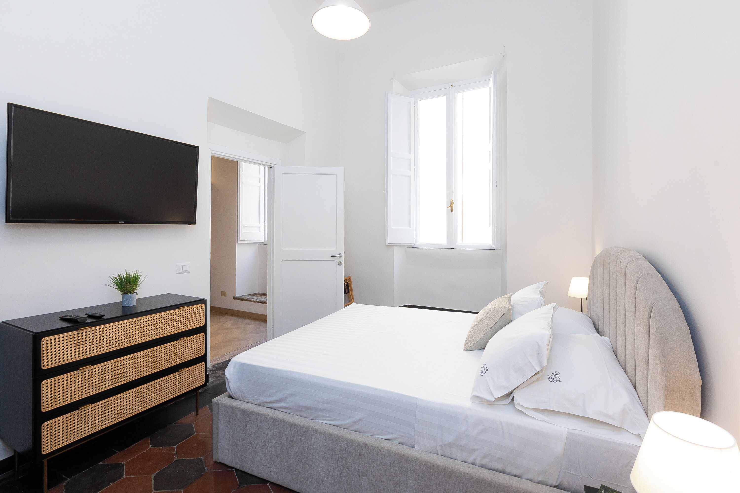 A bedroom with a bed, a dresser, a television, and a window.
