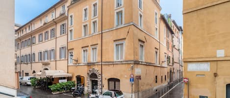 A narrow street with parked cars and a building with a sign reading "VIA RVI DI TOR DI NONA".