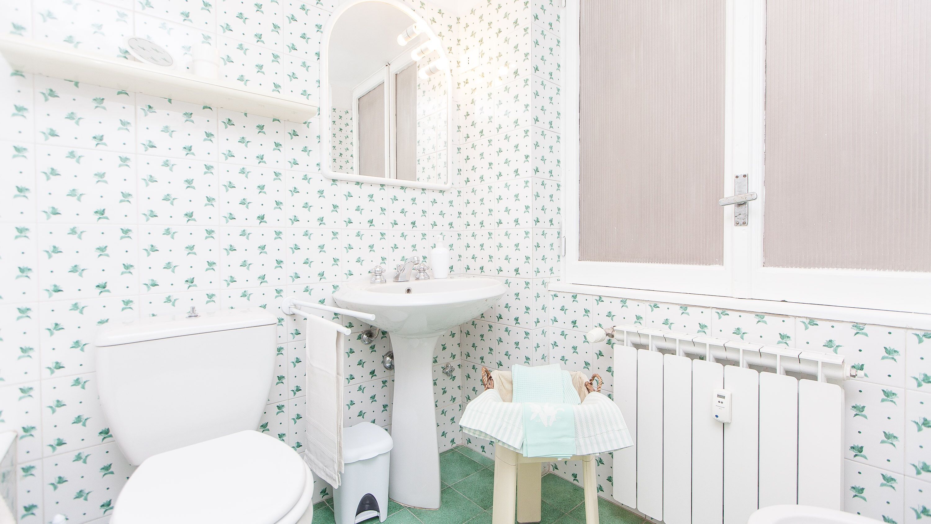 Een badkamer met toilet, wastafel en spiegel.