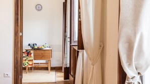 A narrow hallway with a wooden table and a clock on the wall.