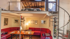 Um apartamento estilo loft com um sofá vermelho, uma mesa de madeira e uma escada.