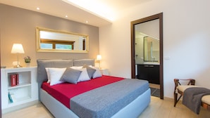 Una camera da letto moderna con un letto grande, lampade ai comodini, uno specchio e un angolo lettura con libri.