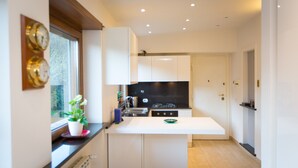 Una cucina moderna con mobili bianchi, un piano di lavoro nero e una finestra vista alberi.