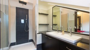 Un bagno moderno con cabina doccia in vetro, uno specchio grande e un mobile doppio lavabo.