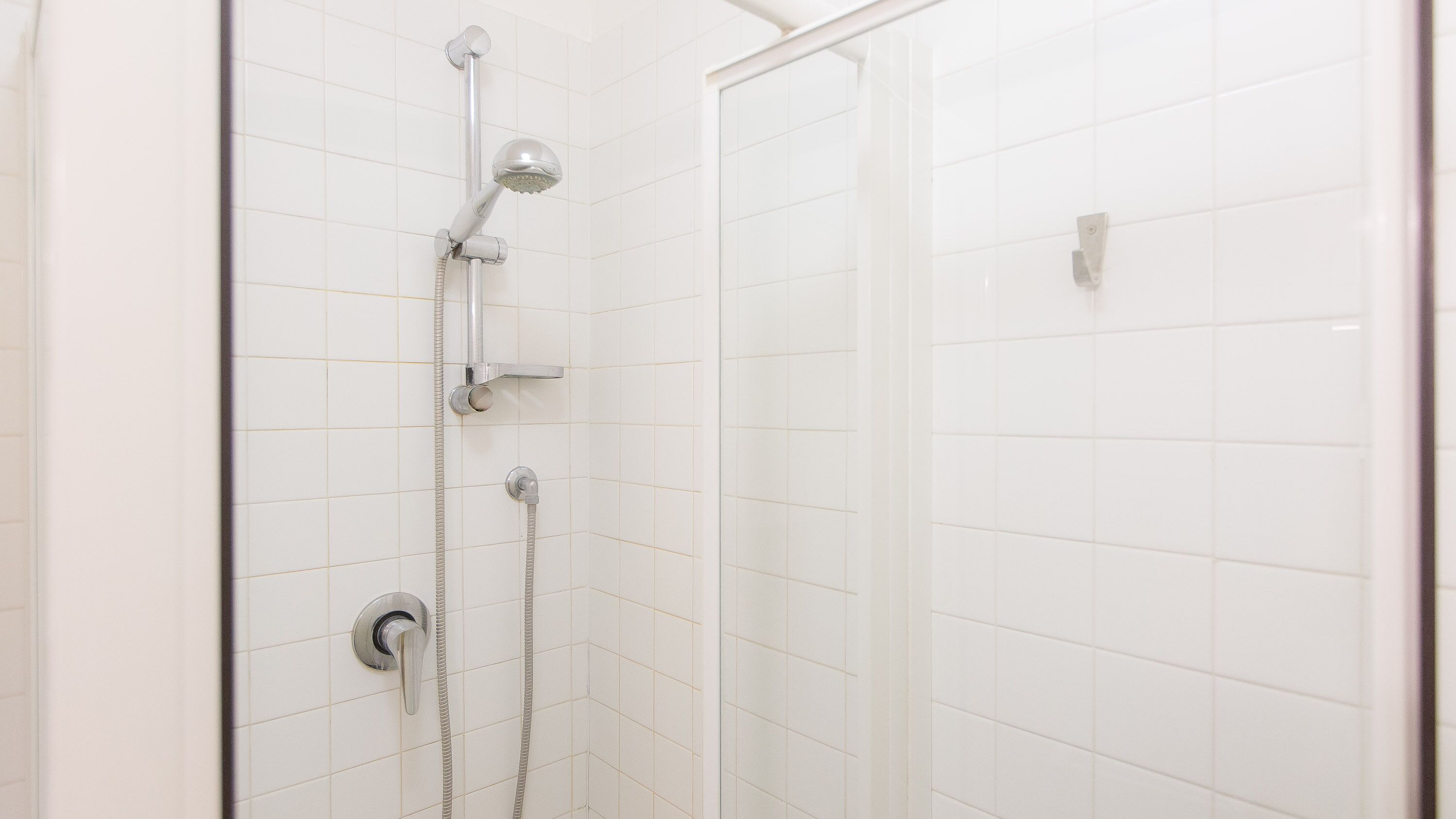 A shower with a handheld showerhead, a wall-mounted showerhead, and a control panel.