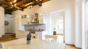 A modern kitchen with white cabinets, a stainless steel range hood, and a wooden countertop. - Rental in Rome Trastevere Atmosphere (Rome)