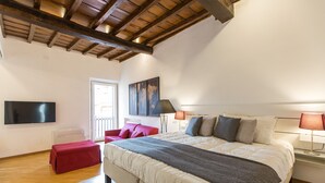 A bedroom with a large bed, a red chair, a flat-screen TV, and a world map on the wall. - Rental in Rome Trastevere Atmosphere (Rome)