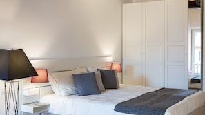 Un lit bien fait, avec des oreillers, une lampe de chevet et une armoire, dans une chambre d’hôtel.