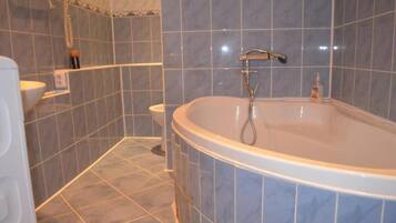 A bathroom with a bathtub, a toilet, and a shower area.