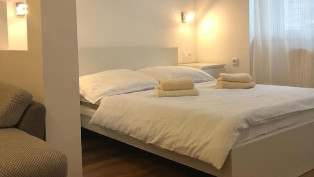 A bedroom with a bed, a sofa, and a wall-mounted picture. - Apartmán Karla Čapka (Teplice)