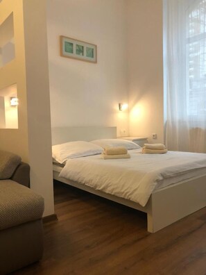 A bedroom with a bed, a sofa, and a wall-mounted picture. - Apartmán Karla Čapka (Teplice)