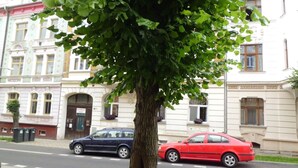 A tree-lined street with parked cars and historic buildings. - Apartmán Karla Čapka (Teplice)