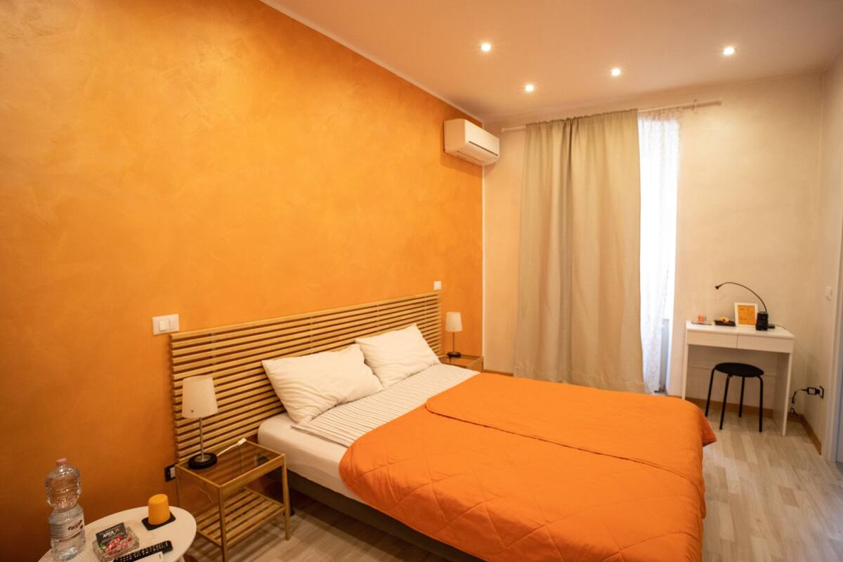 Une chambre d’hôtel comprenant un lit, une table de chevet, une lampe et un bureau avec une chaise.