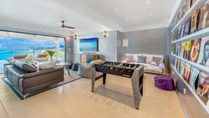 A modern living room with a foosball table, a sofa, and a television. - Villa Amandara (Les Terres Basses)