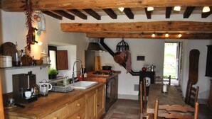 Una cocina rústica con armarios de madera, una isla central y una zona de comedor con sillas de madera.