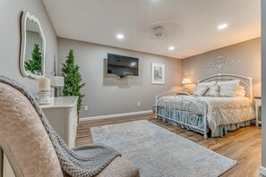 A bedroom with a bed, a TV, a mirror, a dresser, and a small Christmas tree.