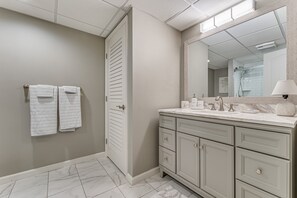 A bathroom with a marble floor, a vanity with a mirror, and two towels hanging on the wall.