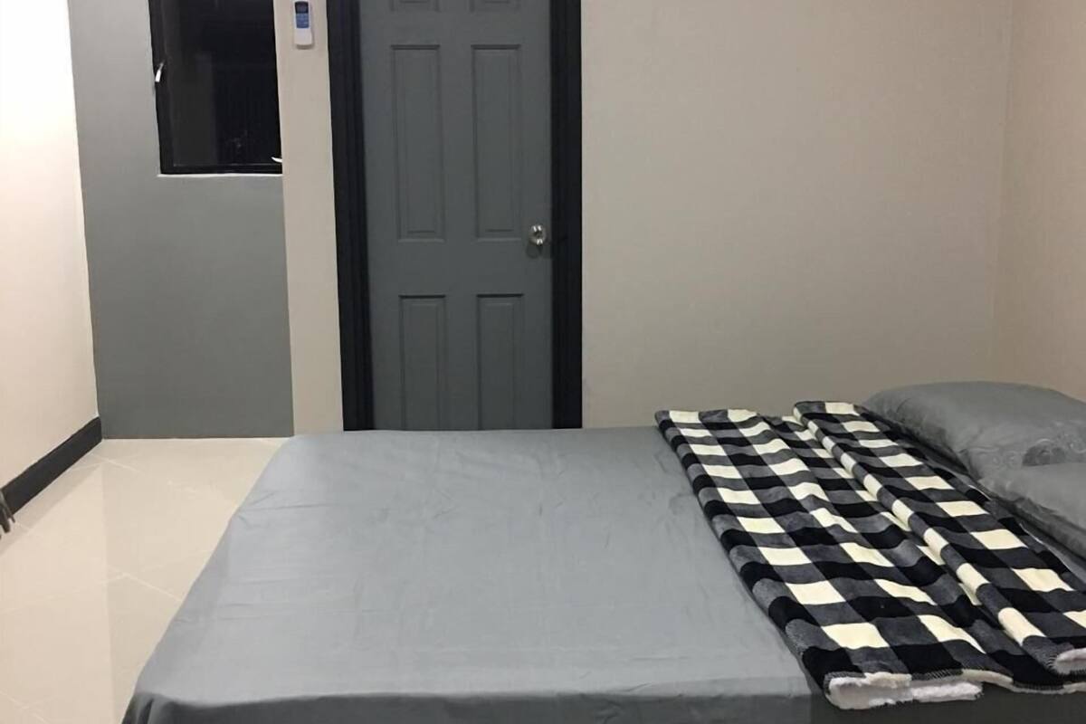 A bedroom with a bed, a door, and an air conditioning unit.
