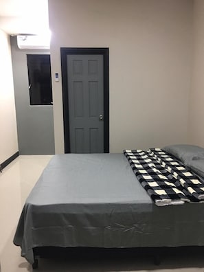 A bedroom with a bed, a door, and an air conditioning unit. - Island Vibes Suites (Port of Spain)
